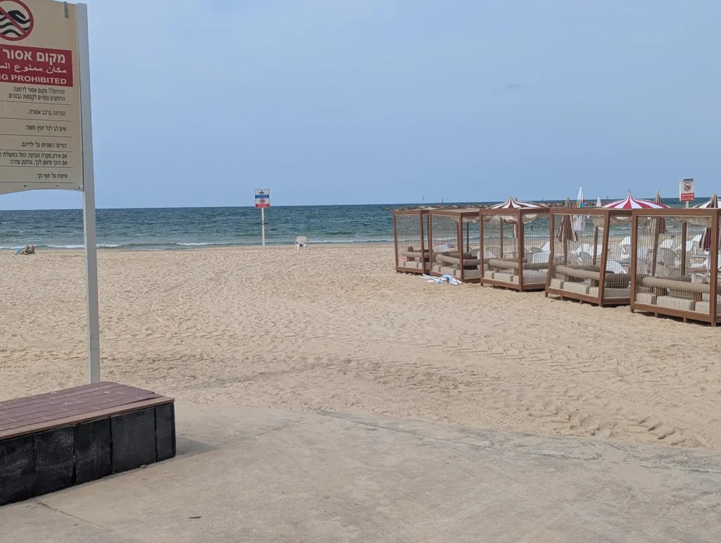 No-swimming sign and cabana loungers on the sand near Banana Beach
