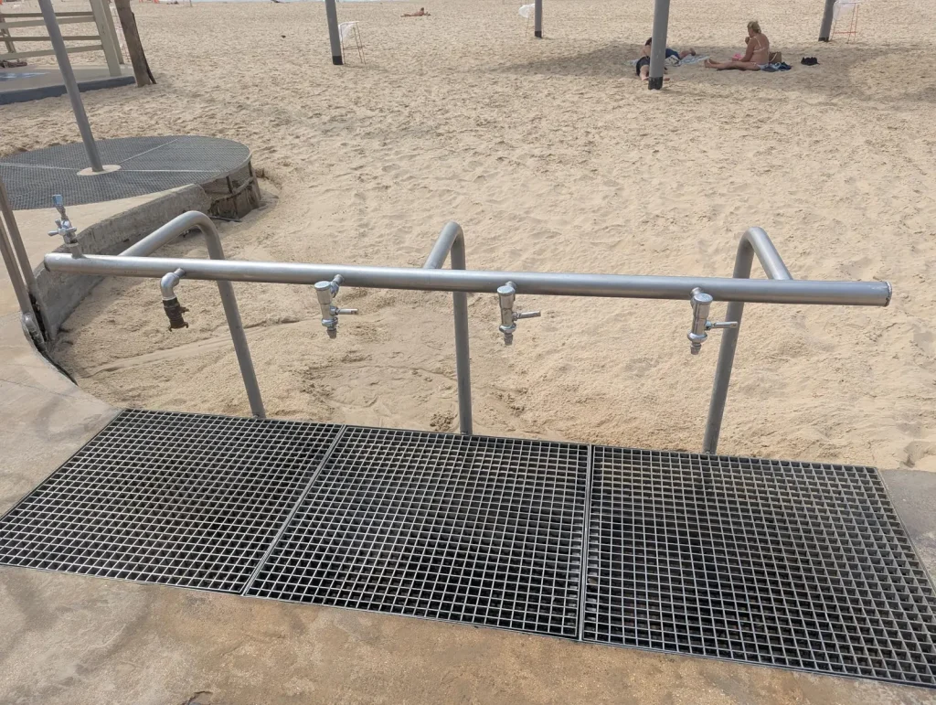 Foot shower with a metal grate on the sand at a Tel Aviv beach