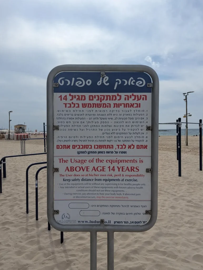Rules sign at the outdoor gym on the sand: equipment for ages 14 and up, use at your own risk