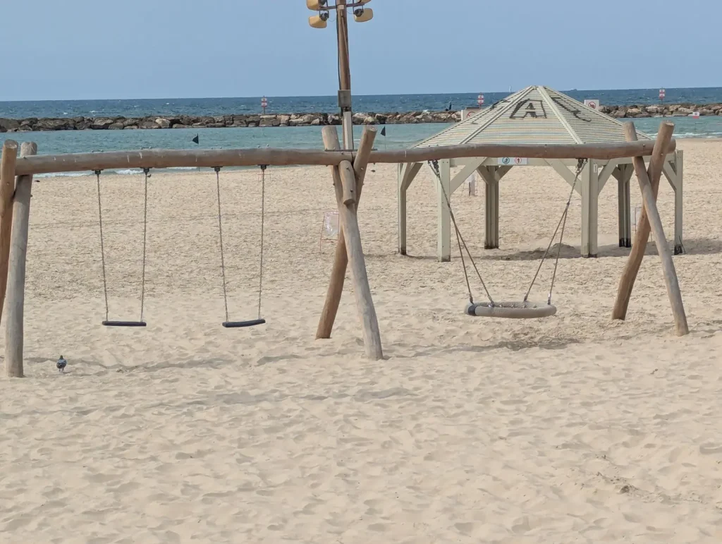 Beach swings with the breakwater behind