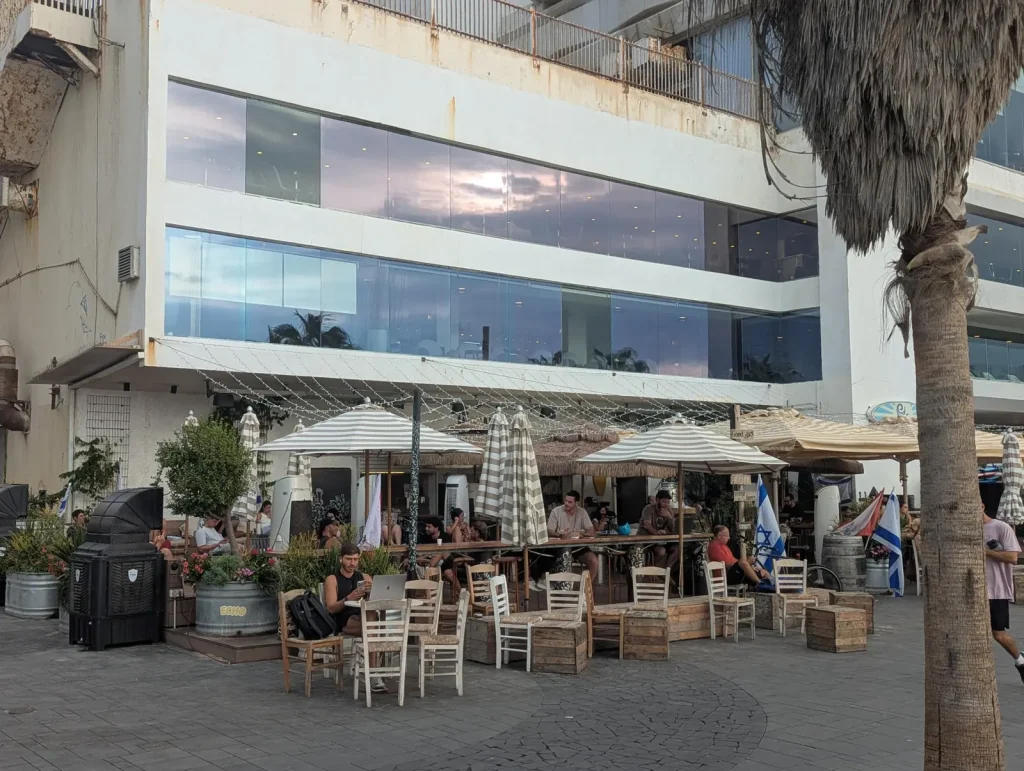 Beachfront cafe terrace with outdoor tables on the Gordon Beach promenade