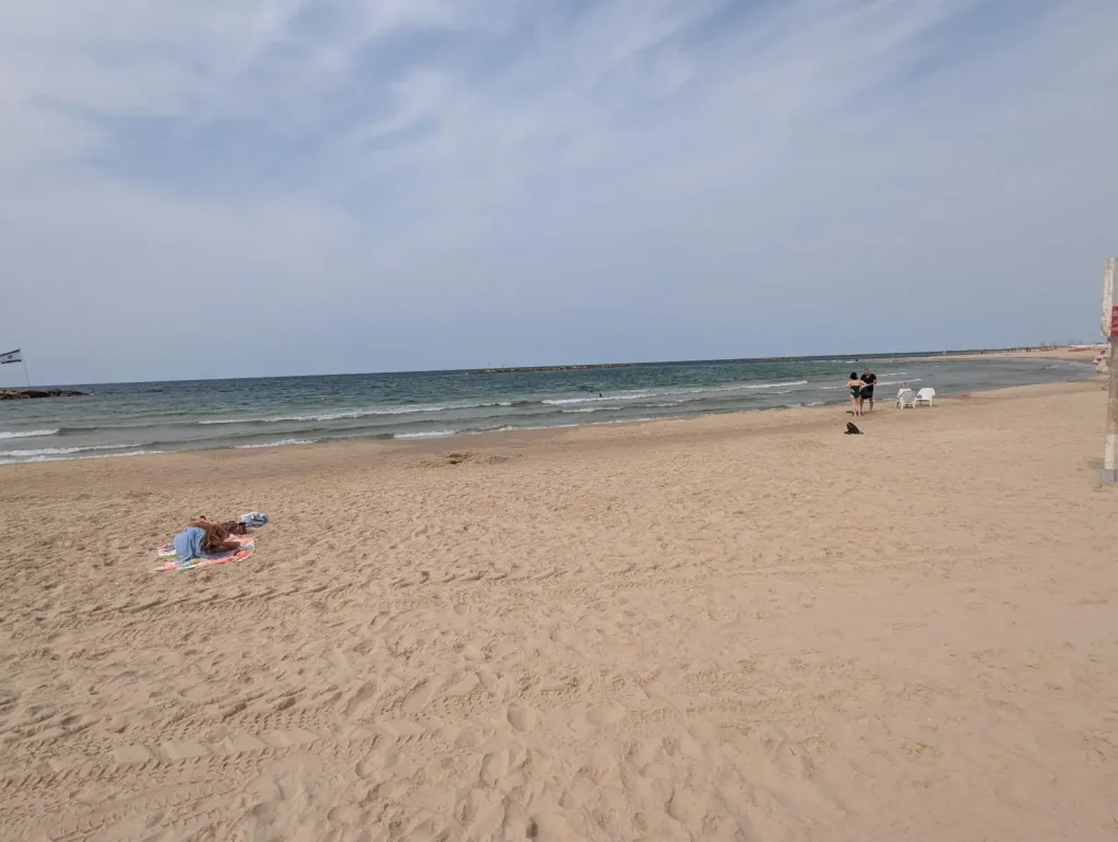 Nearly empty sand at Charles Clore Beach with one sunbather