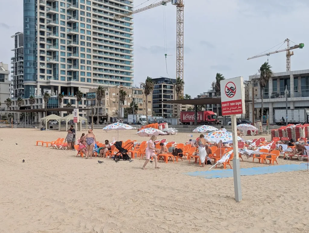 No-swimming sign and orange beach chairs at Jerusalem Beach