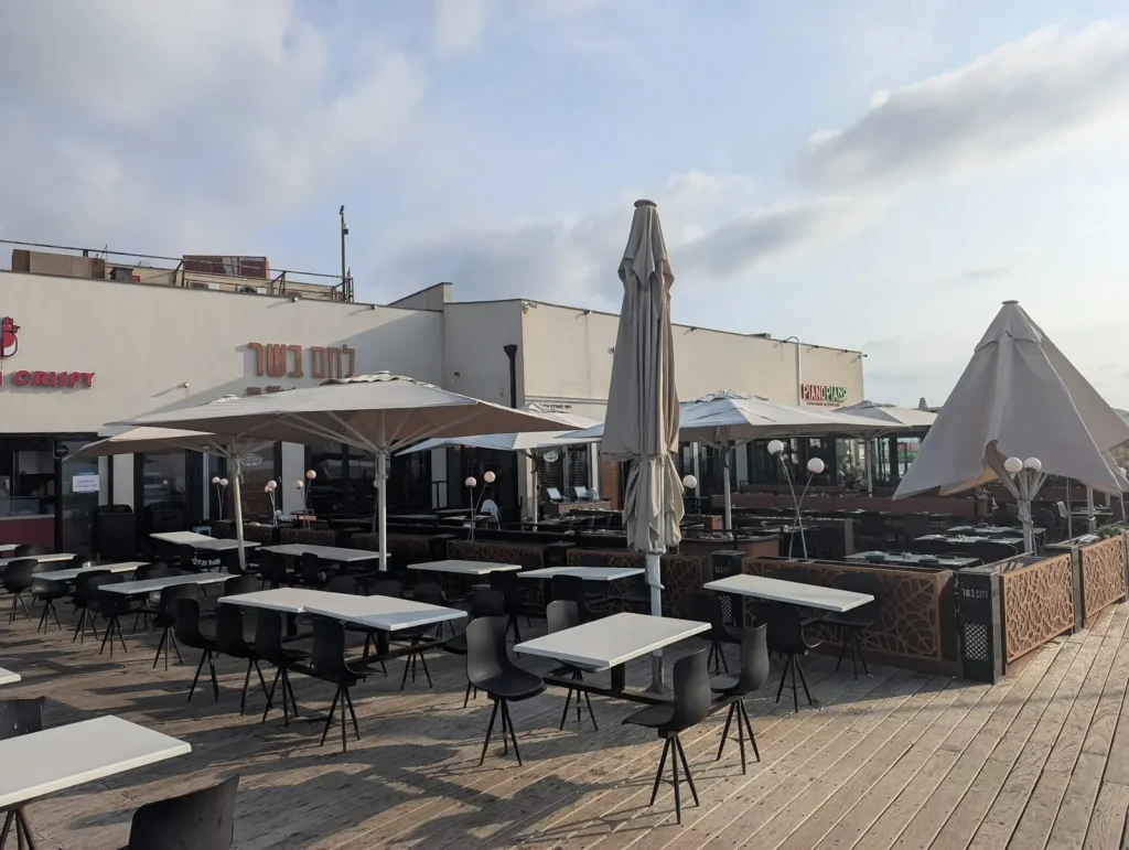 Outdoor terrace of Lechem Basar with umbrellas on the port deck