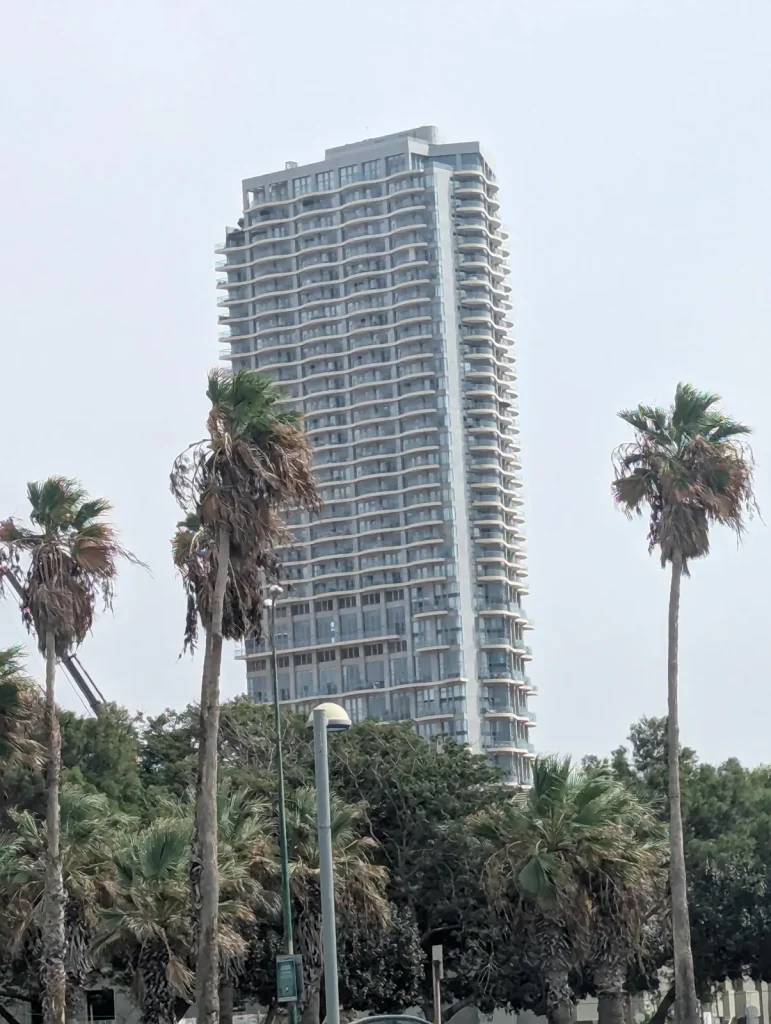 Neve Tzedek Tower rising behind palm trees near Charles Clore Park