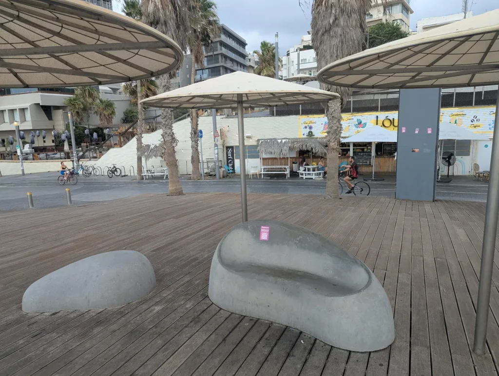 Rounded benches and umbrellas on the promenade near Gordon Beach