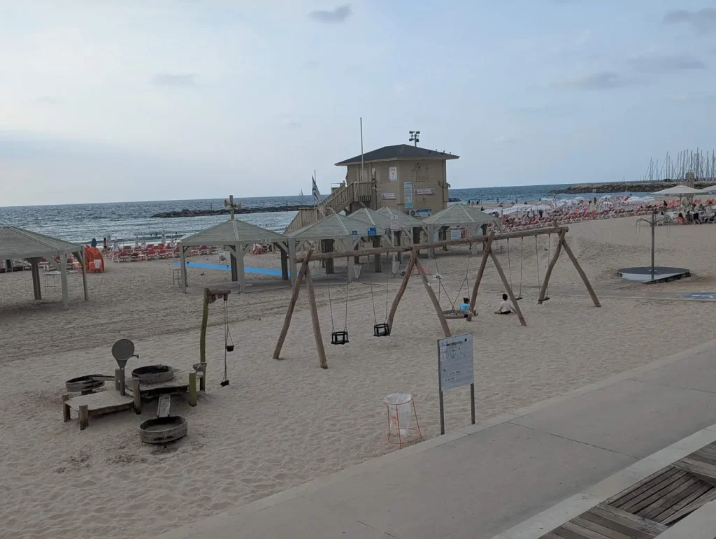 Wooden swing set on the sand at Gordon Beach near a lifeguard tower